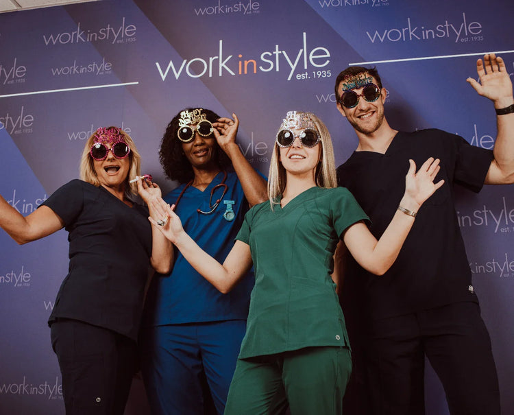 Group of healthcare professionals in colorful medical scrubs celebrating with party glasses