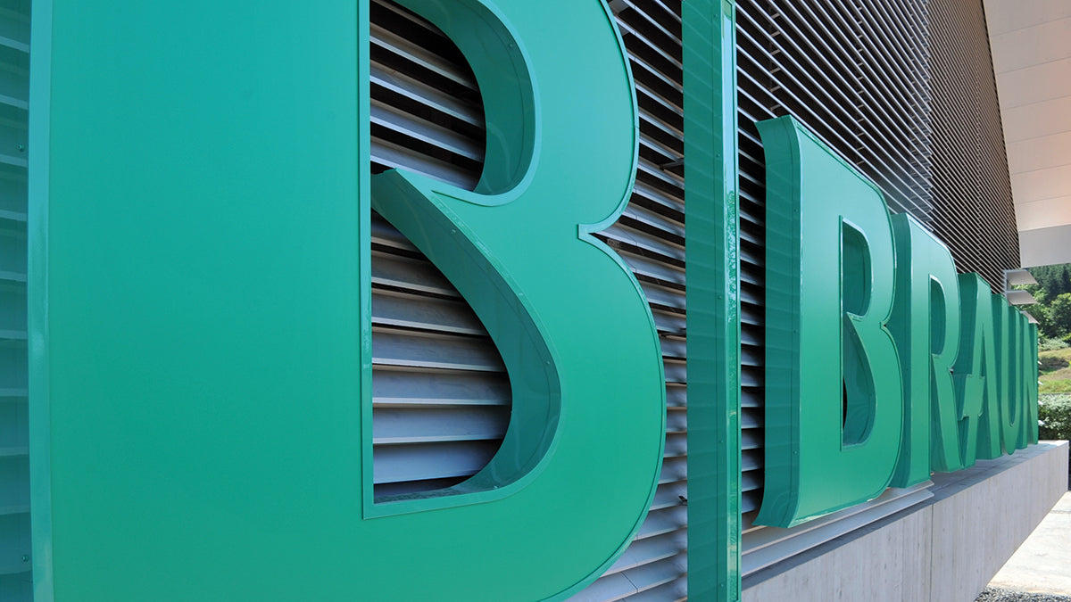 Large green commercial building letters on exterior wall, modern medical facility