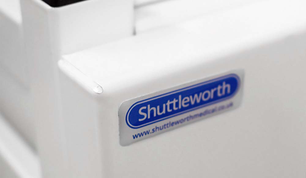 Close-up of Shuttleworth label on white medical equipment, blue text with website link