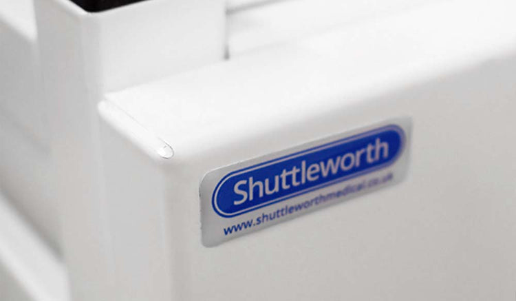 Close-up of Shuttleworth label on white medical equipment, blue text with website link