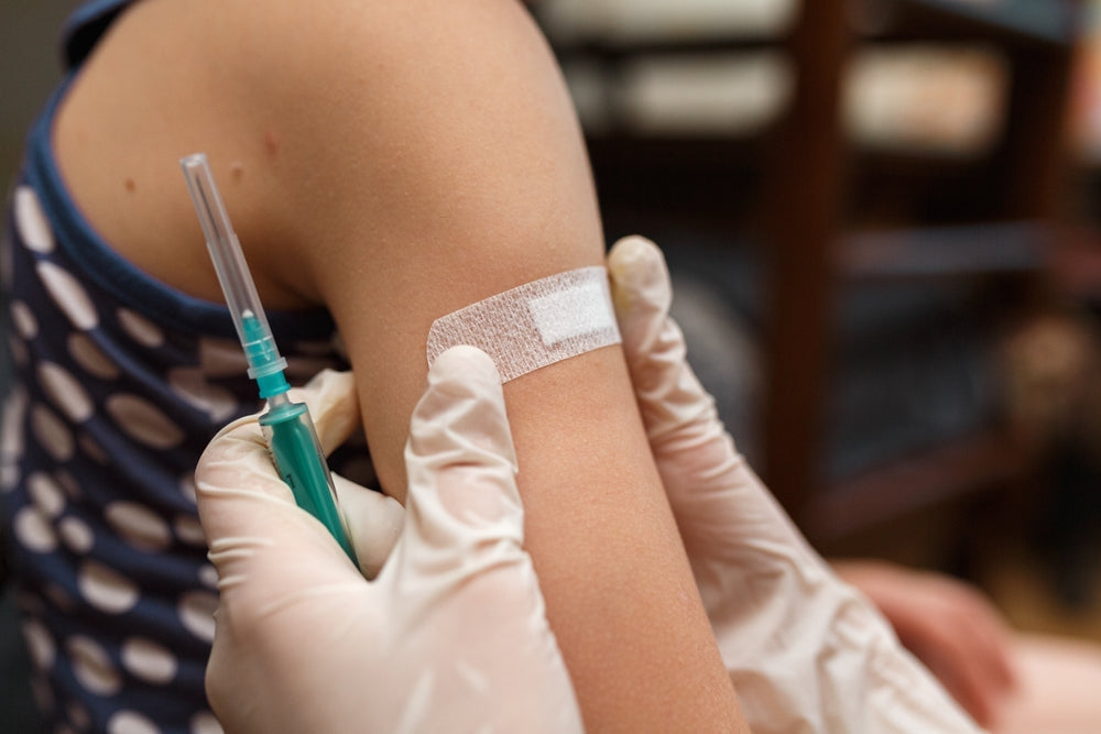 Medical adhesive tape applied to arm after injection, close-up of healthcare procedure