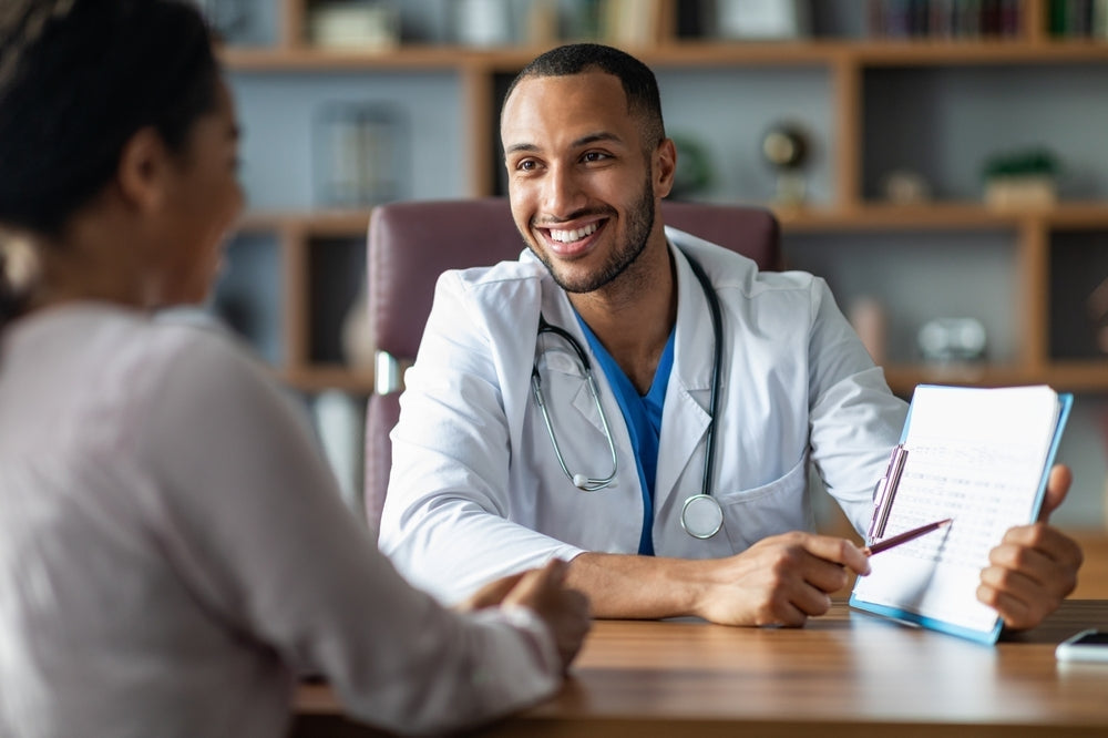 Smiling doctor with stethoscope shows medical chart to patient during consultation