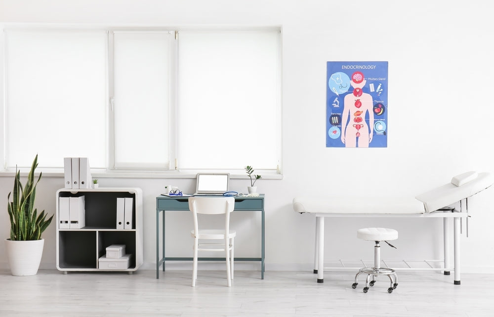 Modern medical exam room with examination couch, desk, plant, and endocrinology poster