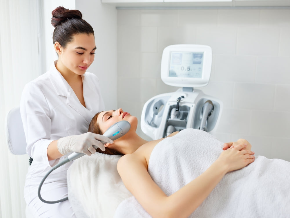 Dermatologist performing facial treatment with a handheld device in a medical clinic