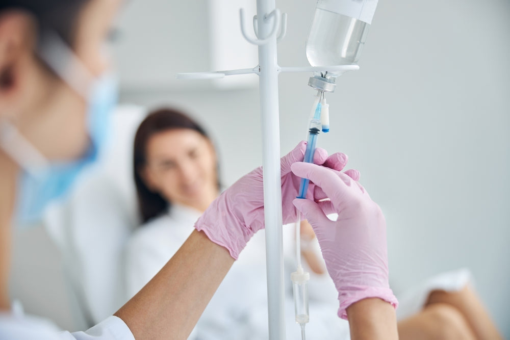 Nurse in gloves preparing IV drip for patient in medical clinic