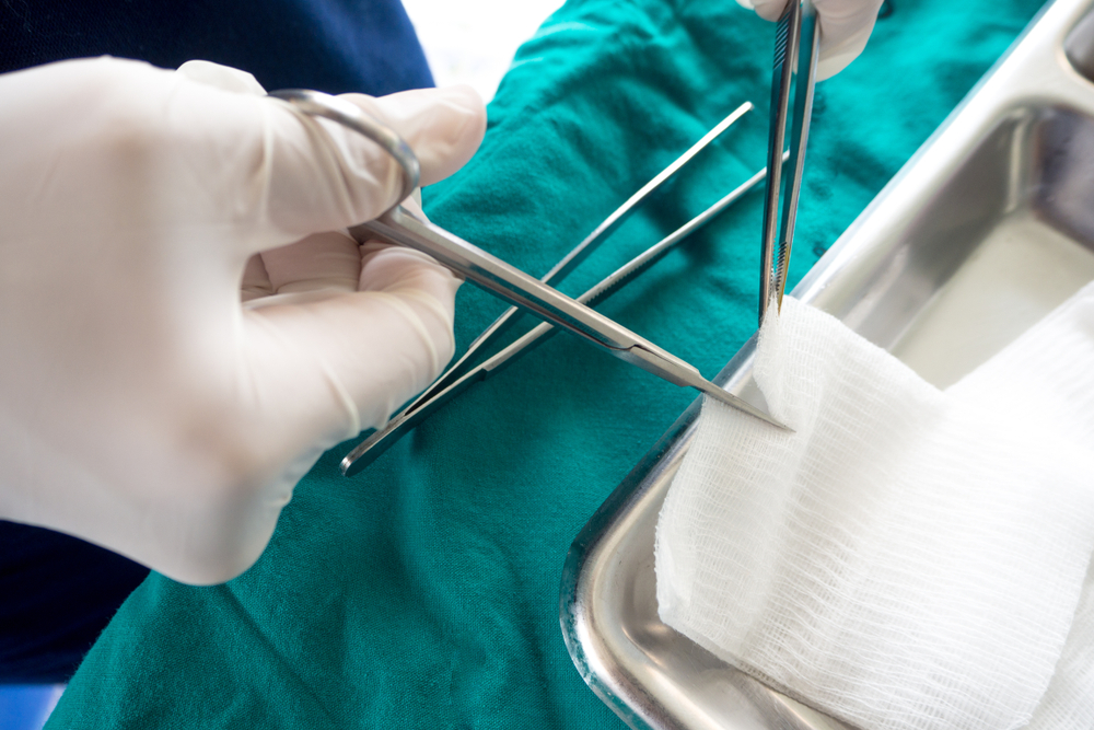 Medical professional with gloves using forceps to handle sterile gauze dressing for wound care