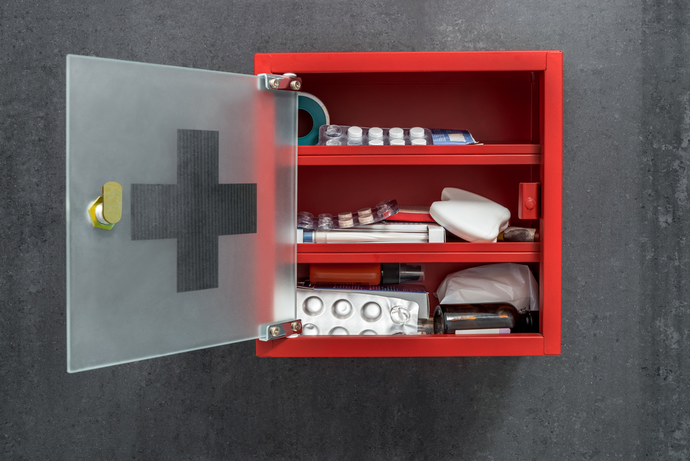 Red metal drug cabinet with glass door, medical supplies and medicines inside