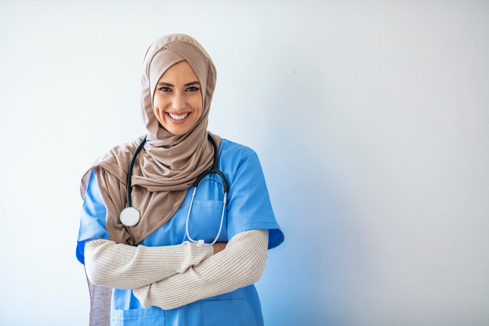 Smiling female healthcare worker in blue scrubs with stethoscope and hijab