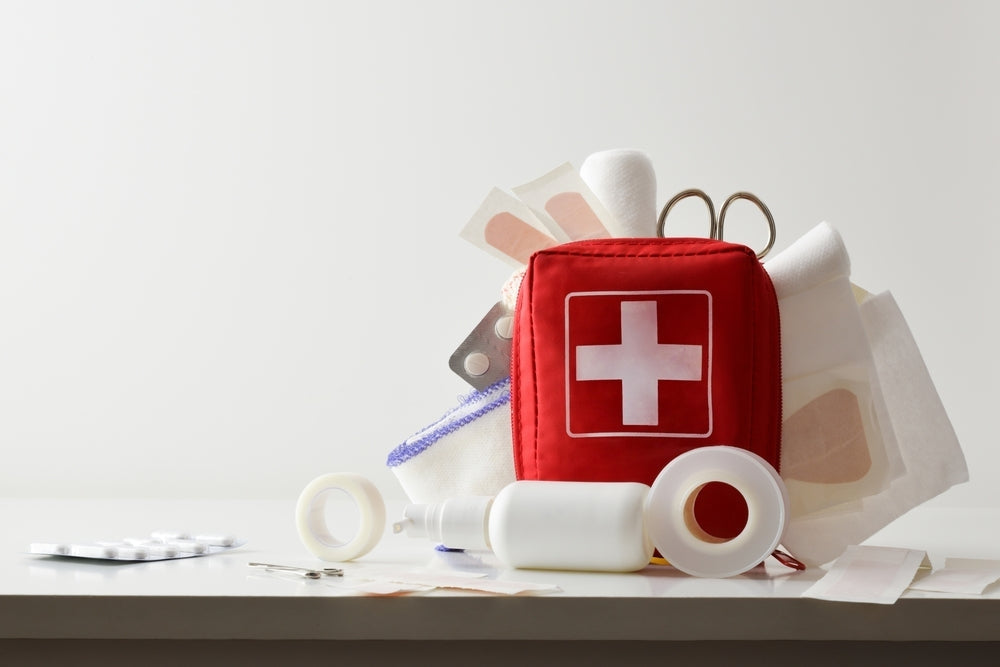 First aid kit with medical supplies including bandages, scissors, adhesive tape, and tablets