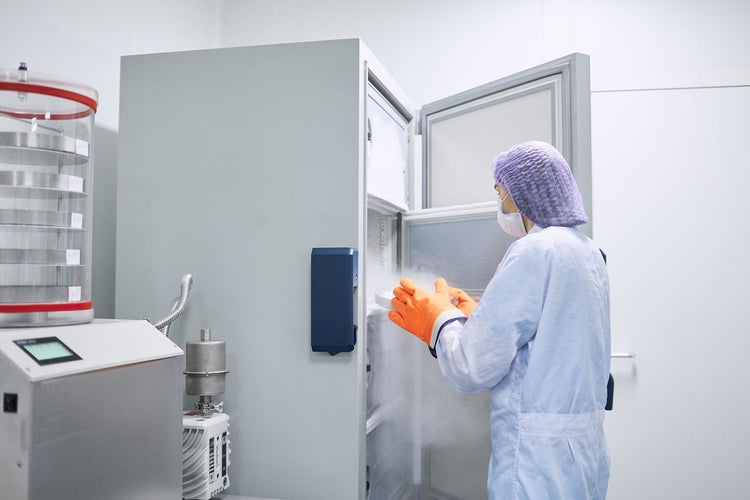 Lab technician in PPE using medical freezer in sterile laboratory environment