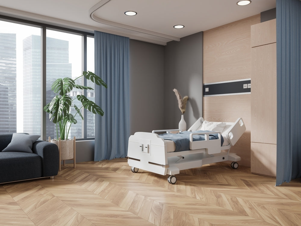 Modern hospital room with adjustable medical bed, large windows, and contemporary furnishings