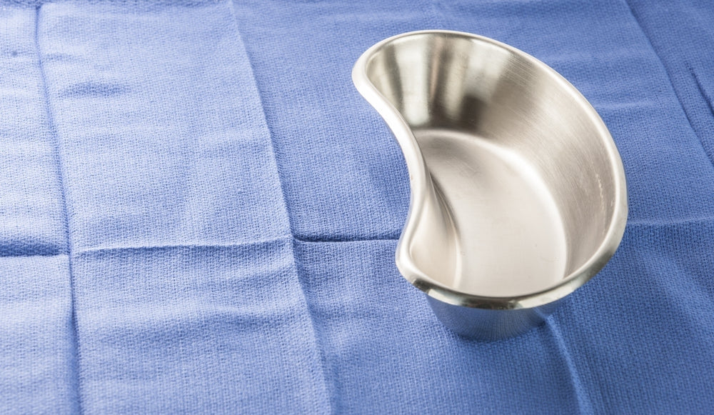 Stainless steel kidney dish on blue surgical cloth, medical holloware