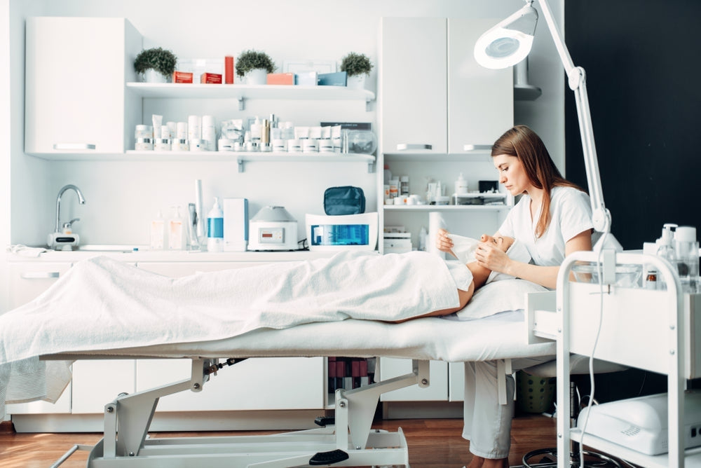 Aesthetic clinic treatment room with a practitioner using medical aesthetic supplies on a patient