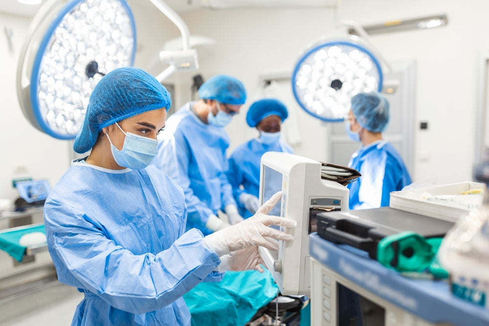Medical team in surgical scrubs monitoring patient vital signs in hospital operating room