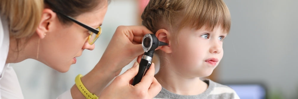 Healthcare professional using otoscope to examine child's ear during medical checkup