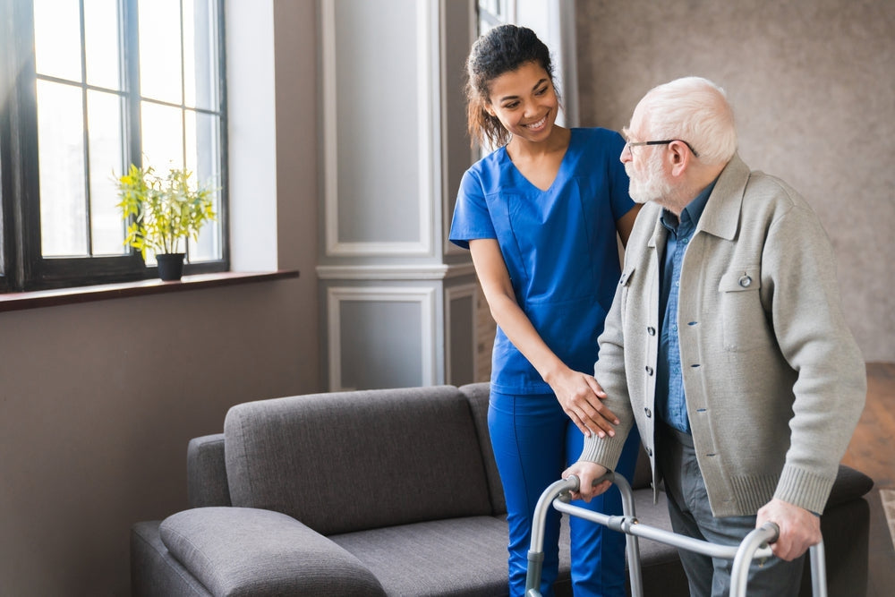 Caregiver assisting elderly man with walker in home setting, patient aid support