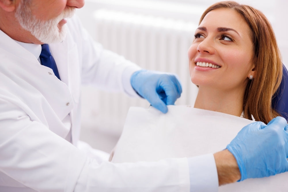 Female patient sitting on medical chair while healthcare professional prepares for dental or medical exam