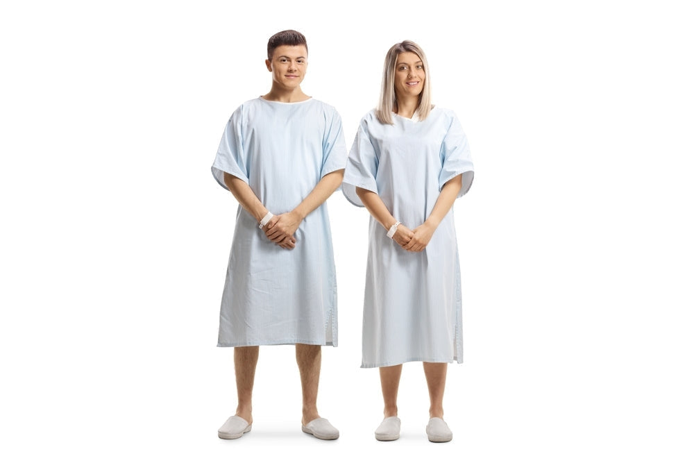 Male and female models wearing light blue patient gowns and hospital slippers