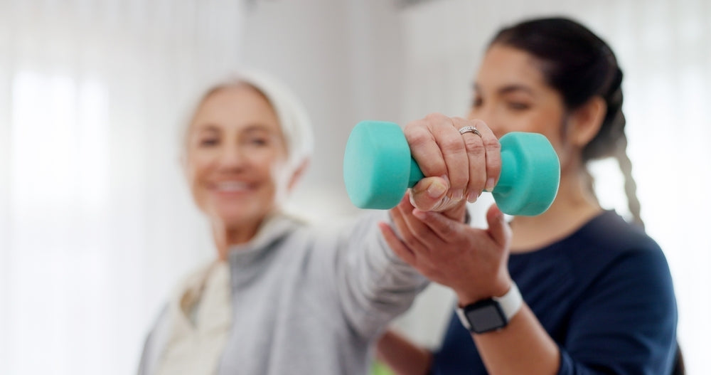 Physiotherapist assisting senior woman with rehab exercise using a light dumbbell