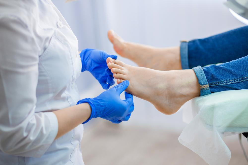 Podiatrist in gloves examining patient’s foot during podiatry consultation