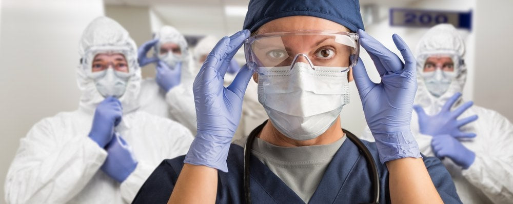 Healthcare workers wearing protective PPE gear, gloves, masks, goggles in hospital hallway