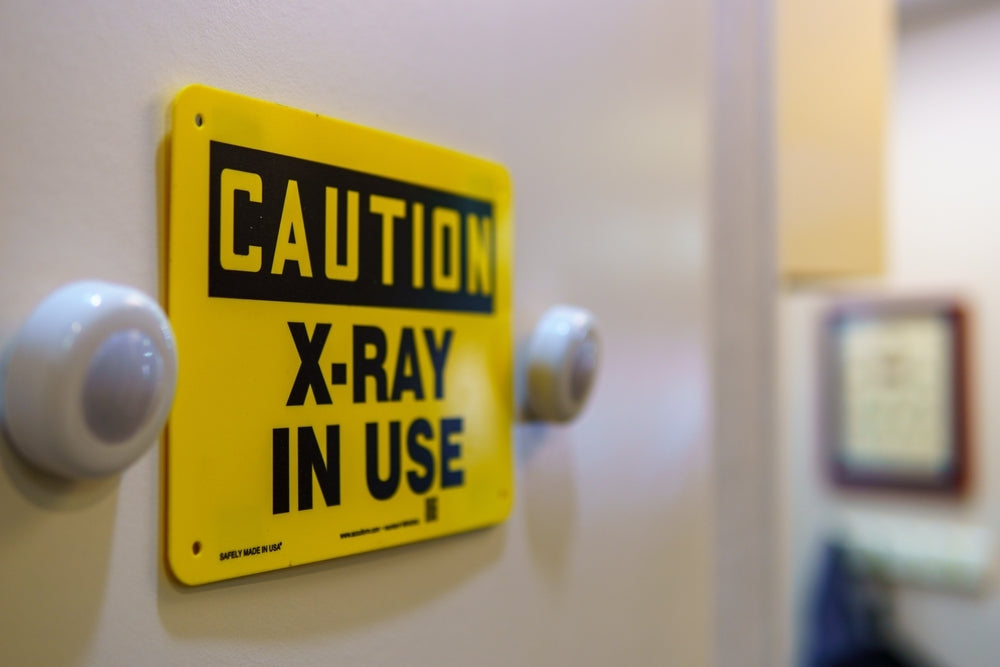 Yellow caution X-ray in use warning sign on a medical facility door
