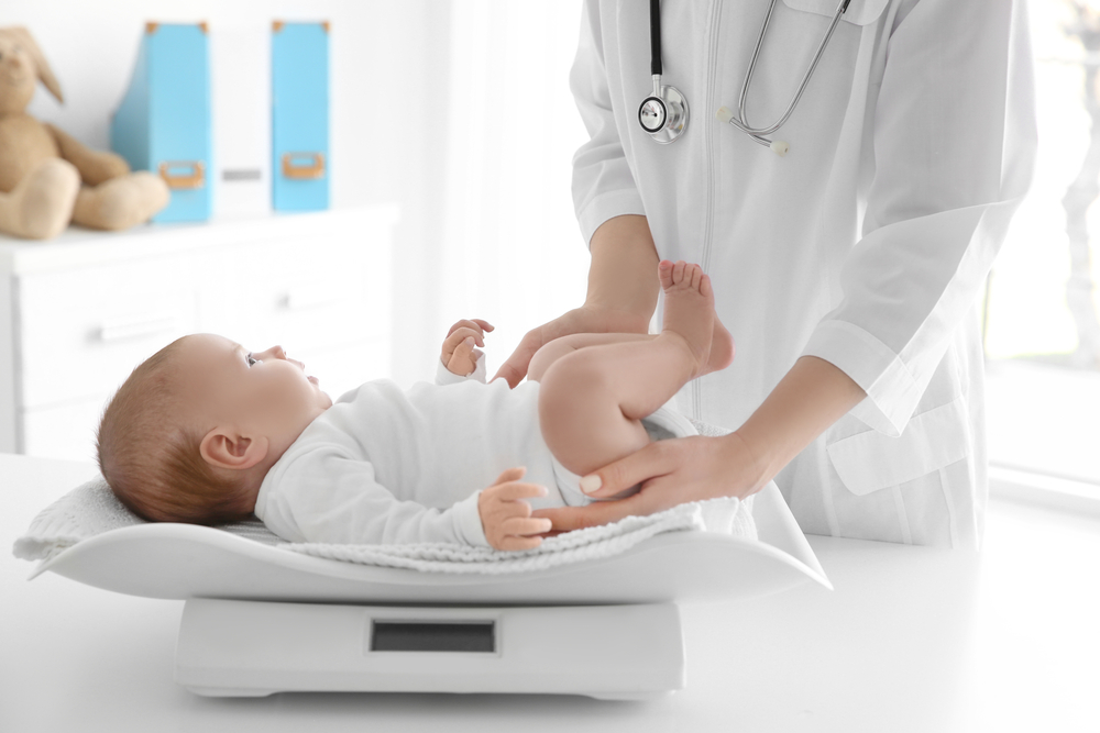 Healthcare professional weighing infant on digital baby scale in clinic setting