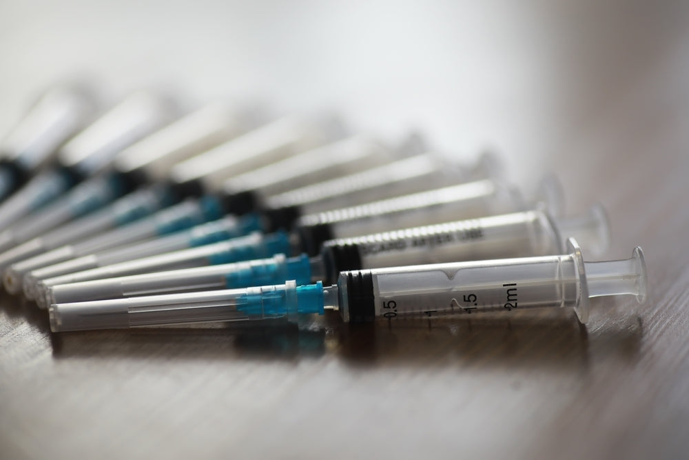 Single-use medical syringes arranged on a wooden surface, sterile disposable instruments