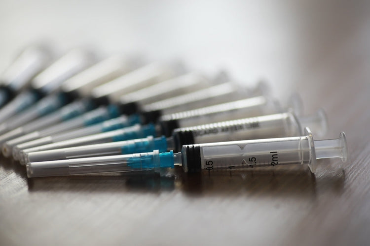 Single-use medical syringes arranged on a wooden surface, sterile disposable instruments