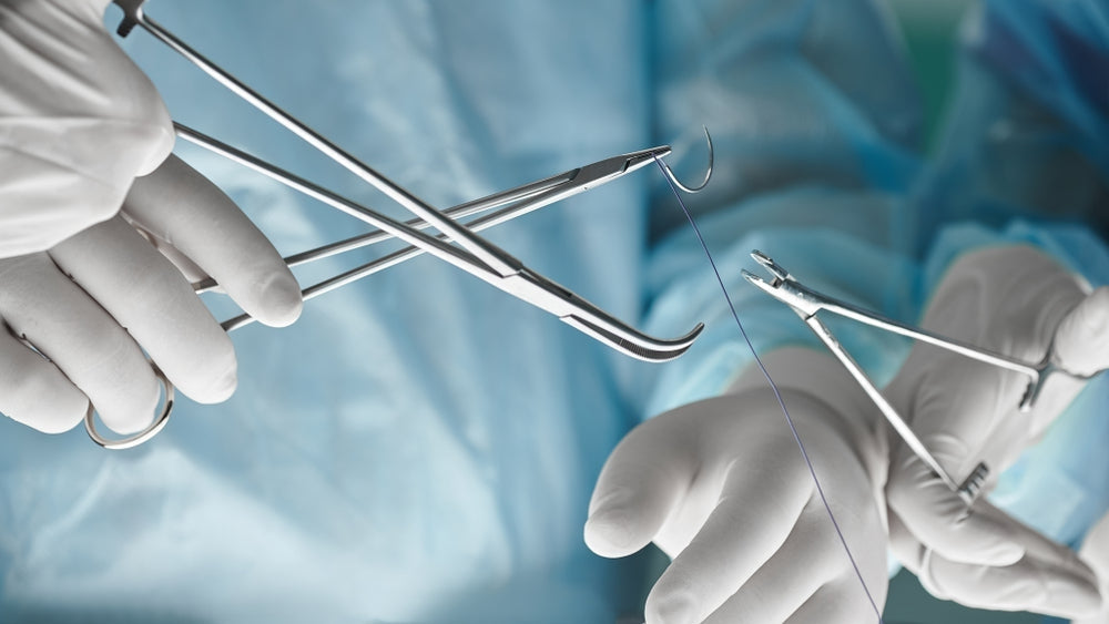 Surgeons using sutures and needle holders in a sterile operating room setting