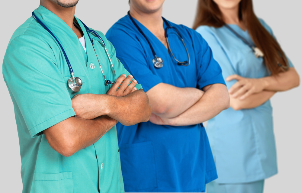 Three healthcare professionals wearing colorful medical uniforms and stethoscopes