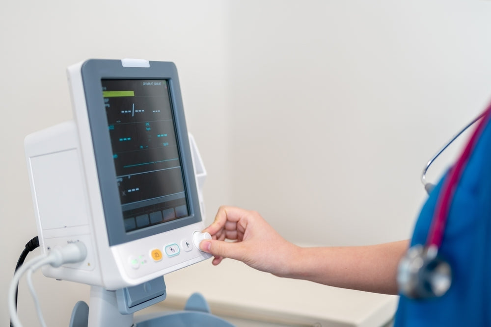 Healthcare worker using a digital vital signs monitor in a clinical setting