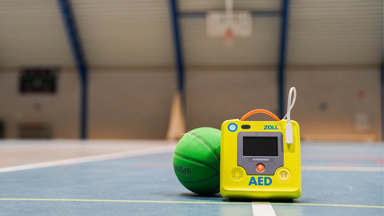ZOLL AED device and green basketball on gym floor, sports emergency medical equipment